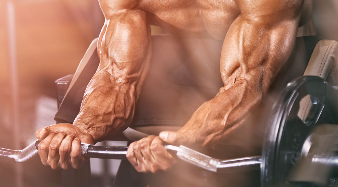 Bodybuilder doing forearm exercises and forearm workouts with preacher curl exercise