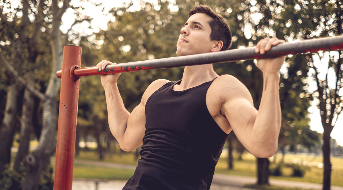 Fit man improving his chin-up performance in the park