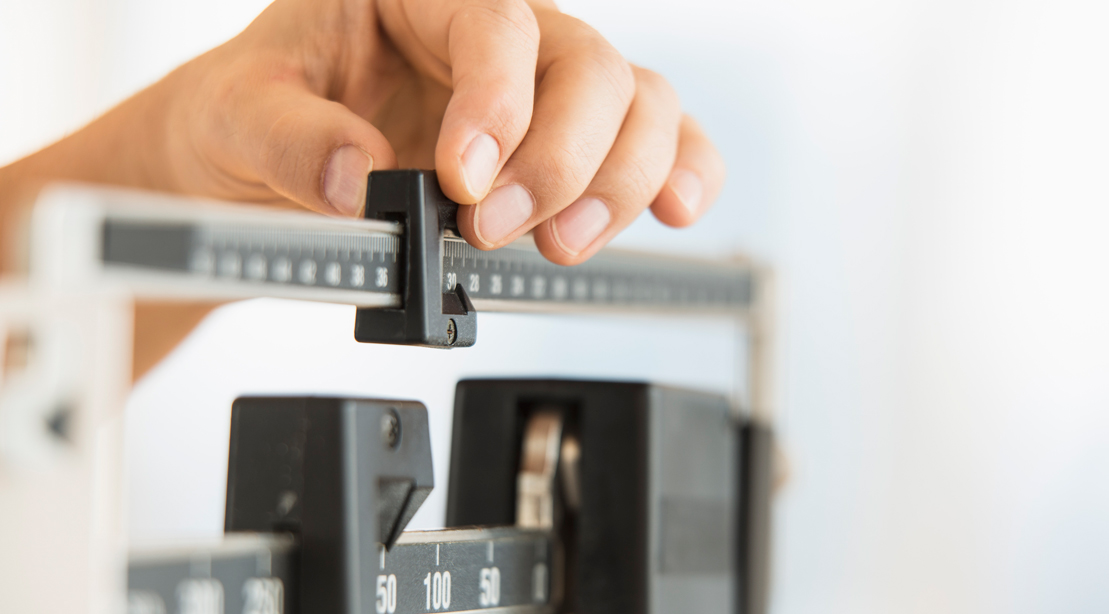 Man weighing himself on a professional scale for a marathon and his new diet plan