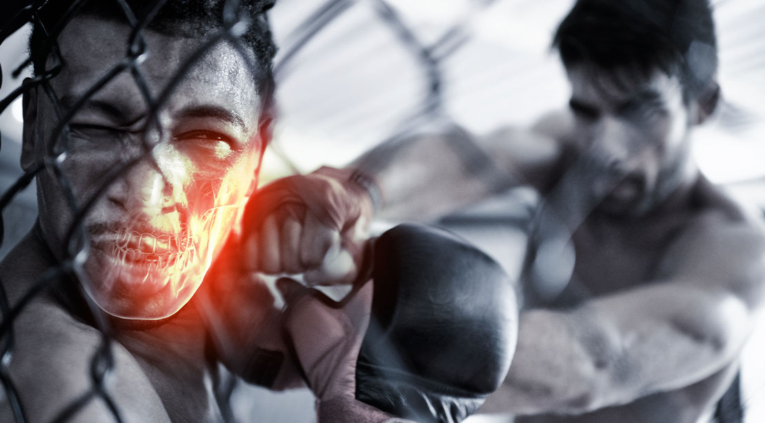 MMA fighter against the cage while his opponent punches his jaw